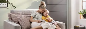 blonde Frau mit Kind schaut Möbelkatalog auf Sofa